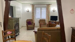 A living room with a sofa, chairs, a television, a fireplace, and a dining table.