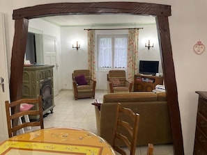 A living room with a sofa, chairs, a television, a fireplace, and a dining table.