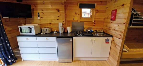 A compact kitchen with a microwave, toaster, sink, and a small window.