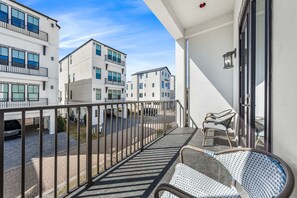 Ein Balkon mit Blick auf angrenzende Gebäude, einem Metallgeländer und zwei Korbstühlen.