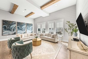 Ein modernes Wohnzimmer mit einem Ecksofa, zwei Sesseln, einem Couchtisch und einem an der Wand befestigten Flachbildfernseher.