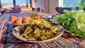 Una mesa de comedor con un plato de verduras cocinadas, huevos y una ensalada, sobre un mantel estampado.