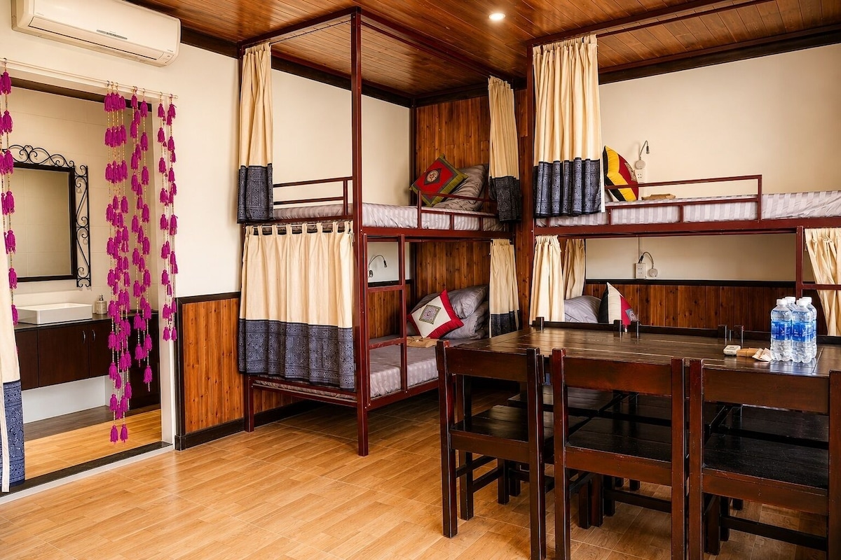 A room with bunk beds, a wooden dining table, and a mirror.