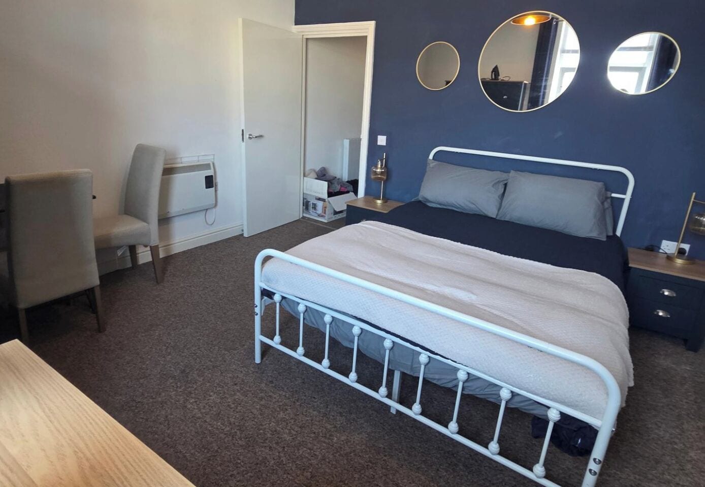 A bedroom with a bed, a chair, a desk, and a wardrobe.