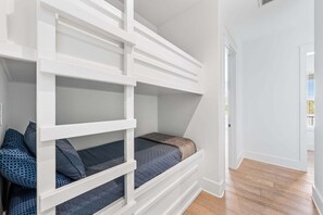 A room with a bunk bed, a door leading to another room, and a wooden floor. - Sleeps 30! LSV/Golf Cart, Private Pool, HotTub, & Game Room! Pet-Friendly (Santa Rosa Beach)