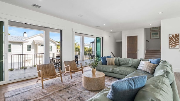 A spacious living room with a green sofa, wicker chairs, a round coffee table, and a view of the outside. - Sleeps 30! LSV/Golf Cart, Private Pool, HotTub, & Game Room! Pet-Friendly (Santa Rosa Beach)
