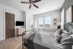 Ein Schlafzimmer mit einem Bett, einem Fernseher, einem Deckenventilator und einem Fenster mit Jalousien.