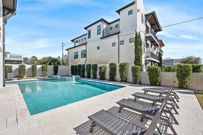 A modern building with a swimming pool and outdoor seating. - Sleeps 30! LSV/Golf Cart, Private Pool, HotTub, & Game Room! Pet-Friendly (Santa Rosa Beach)