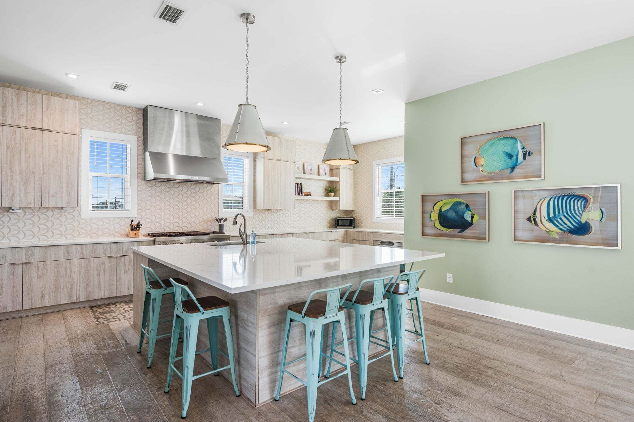 A modern kitchen with a central island, pendant lights, and a backsplash with a geometric pattern.
