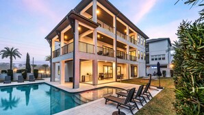 A multi-story building with a pool, outdoor seating, and a well-lit patio area. - Sleeps 30! LSV/Golf Cart, Private Pool, HotTub, & Game Room! Pet-Friendly (Santa Rosa Beach)