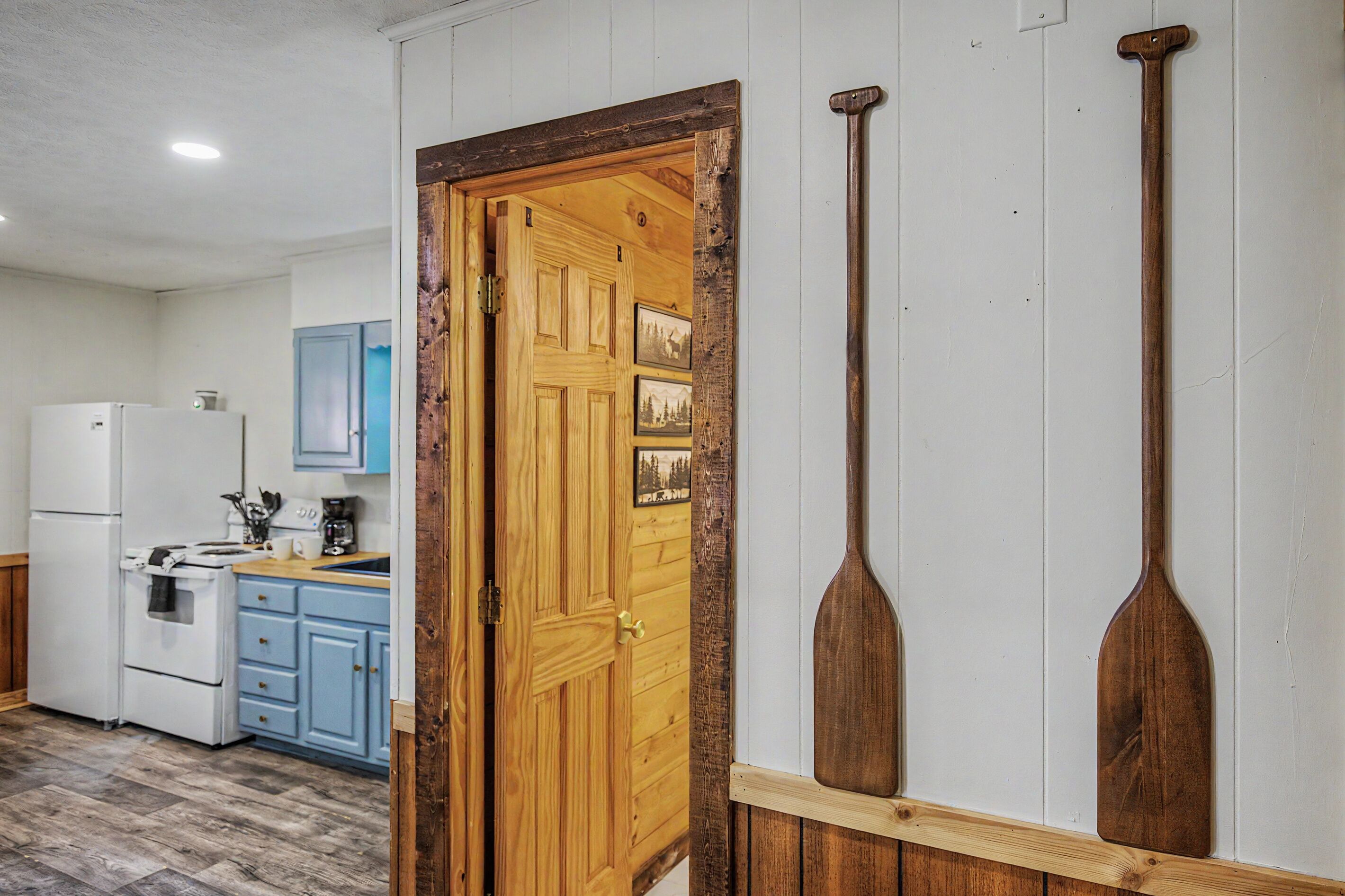 A kitchen with wooden cabinets, a white refrigerator, and a wooden door with a rustic design.