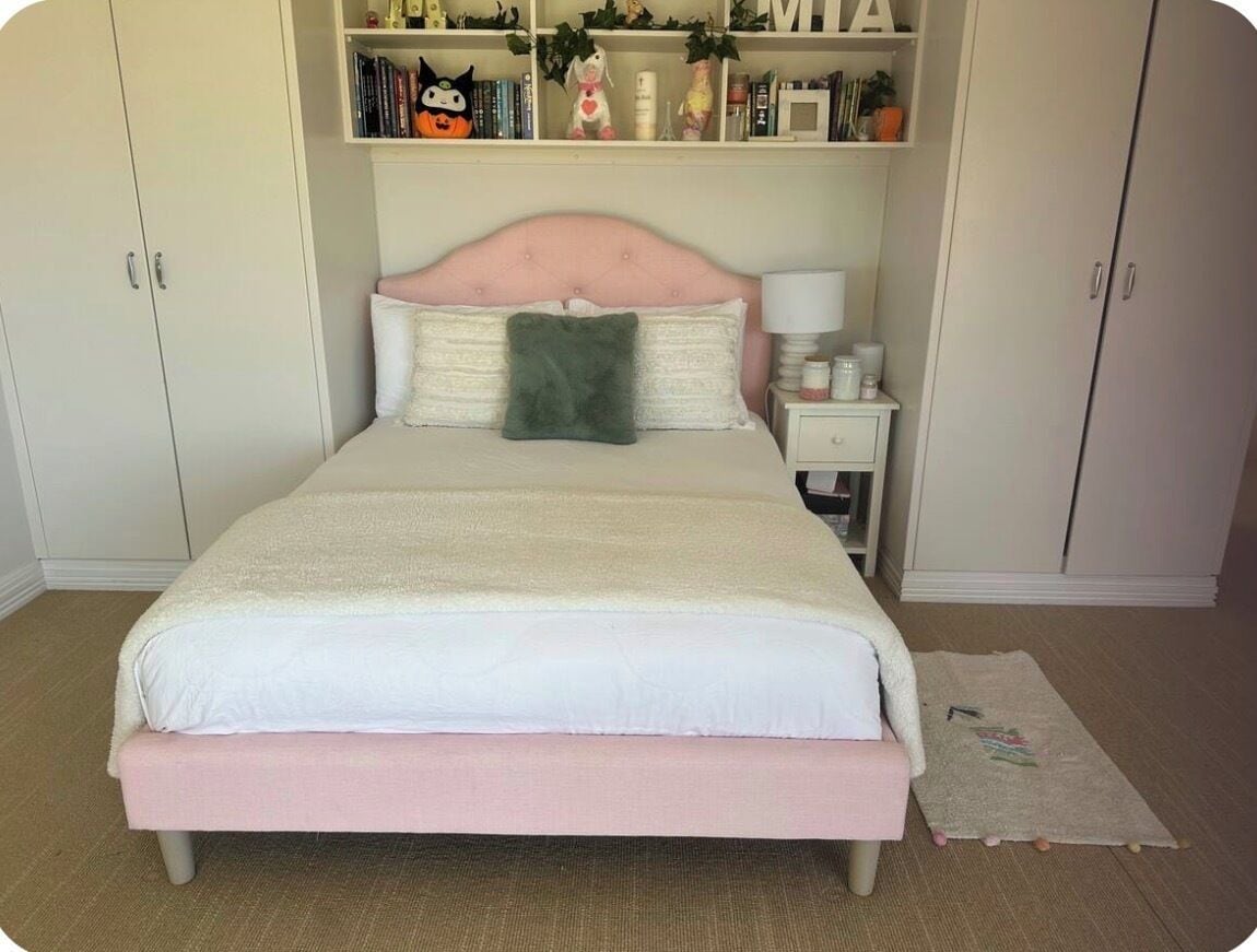 A bedroom with a bed, bedside table, and wardrobe.