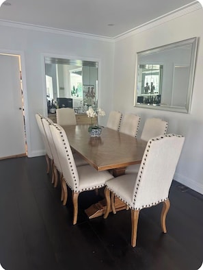 Ein Esszimmer mit einem rechteckigen Holztisch, umgeben von sechs gepolsterten Stühlen mit Ziernähten.