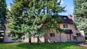 A two-story building with a flat roof, multiple windows, and a well-maintained lawn. - Conveniently located condo w/ fast wifi, great location & shared pool & hot tub (Winter Park)