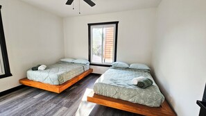 A room with two beds, a window, and a ceiling fan.