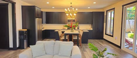 A modern kitchen with dark cabinets, a central island, and a chandelier.