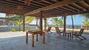 A covered outdoor seating area with wooden furniture and hanging baskets. - Casa Buenas Vibras 5-bedroom Beach Front house in Rio Maria (Rio Maria)