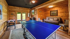 Ein Zimmer mit Tischtennisplatte, einer Couch und Holzvertäfelung.