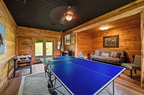 A room with a ping pong table, a sofa, and a wooden interior. - New! Dollywood~Secluded~Hot Tub~King Suite~Firepit (Sevierville)