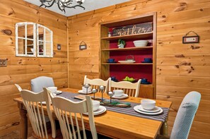 A wooden interior with a dining table set for four, surrounded by chairs. - New! Dollywood~Secluded~Hot Tub~King Suite~Firepit (Sevierville)