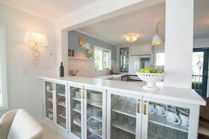 A kitchen with white cabinetry, a marble countertop, and a bowl of fruit on the island.