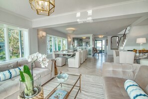 A spacious living area with a dining table, sofas, and a kitchen in the background.