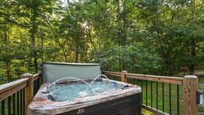 Un jacuzzi en una terraza de madera rodeado de árboles.
