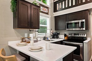 Une cuisine avec des meubles en bois foncé, un four à micro-ondes en acier inoxydable, une cuisinière et un plan de travail en marbre blanc.