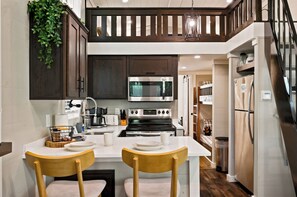 Una cocina moderna con gabinetes de madera oscura, electrodomésticos de acero inoxidable y encimera blanca.