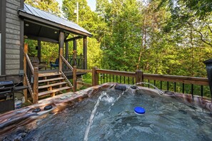 Un jacuzzi con terraza de madera y escaleras que conducen a un área cubierta con mobiliario exterior.