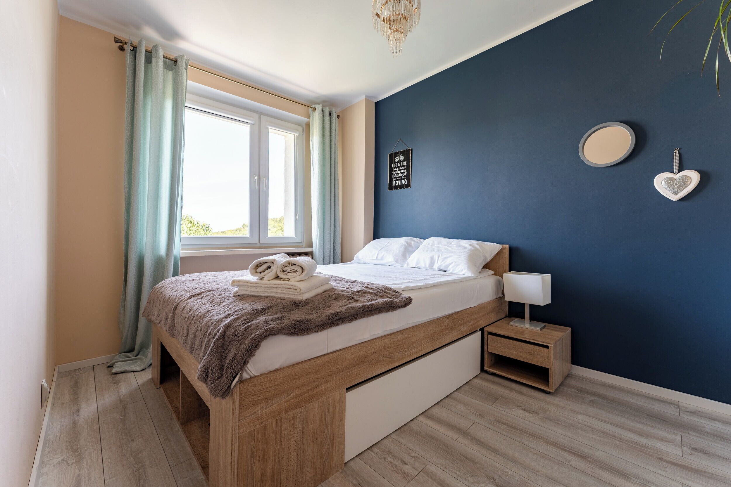 Een slaapkamer met een bed, nachtkastje en een wandlamp.