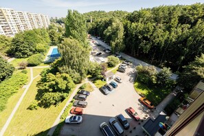 An aerial view of a parking lot with multiple cars, surrounded by trees and a residential area with buildings in the background. - Cieszyńskiego Harmony Apartment (Sopot)