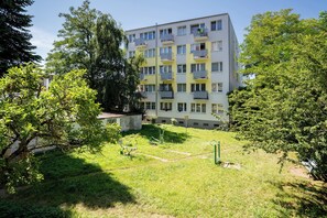 Ein mehrstöckiges Wohnhaus mit Balkonen, einem grünen Innenhof und Bäumen.