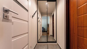 Un pasillo con una puerta corredera de vidrio que da a una habitación con sofá azul y piso de madera.