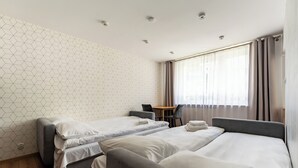 Habitación de hotel con dos camas individuales, una mesita y una silla.
