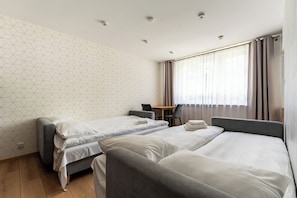 Ein Hotelzimmer mit zwei Einzelbetten, einem kleinen Tisch und einem Sessel.