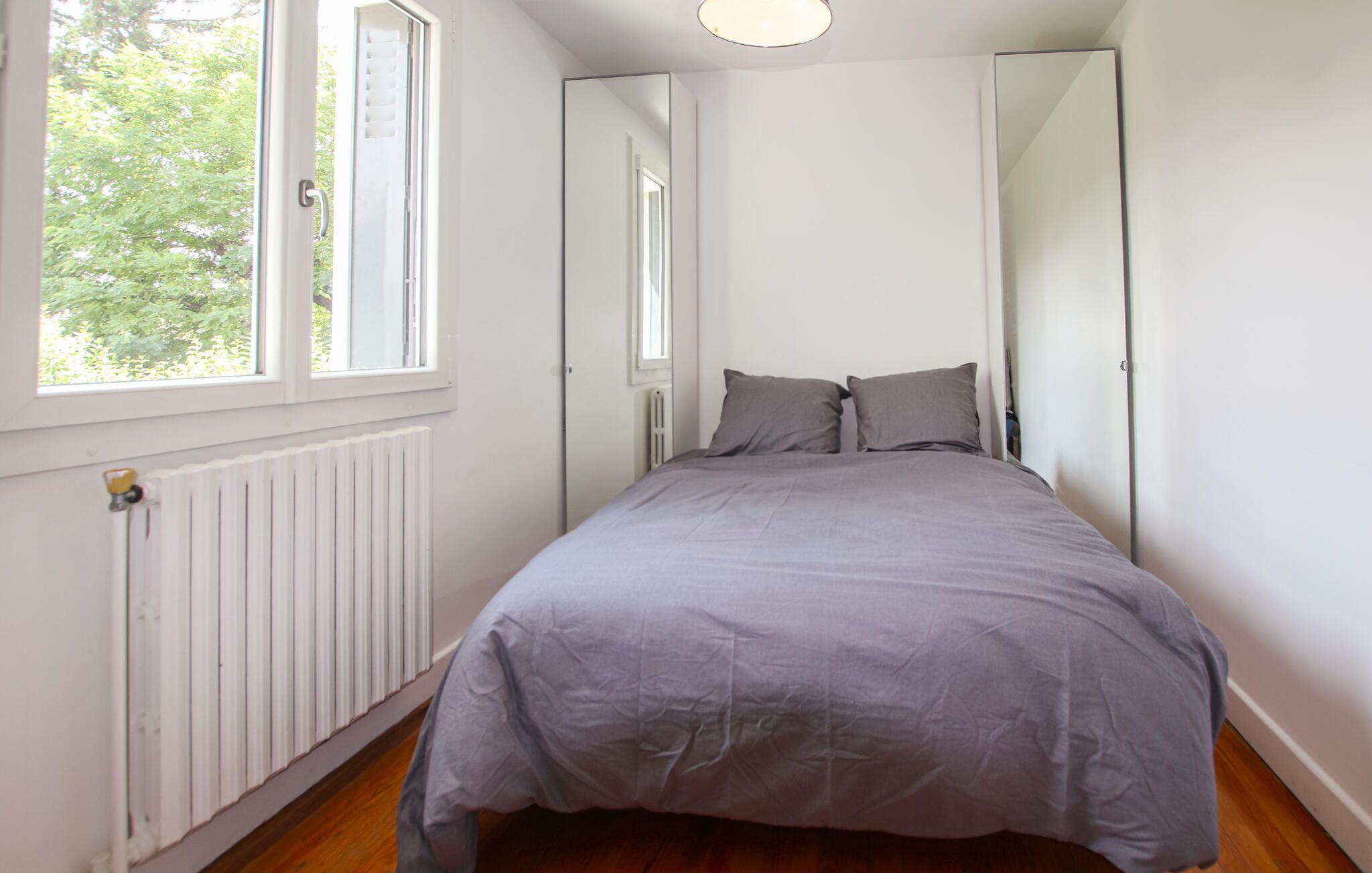 A bedroom with a bed, a window, and a radiator.