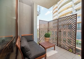 Un balcón con un sofá, una mesa de madera y una planta en maceta.