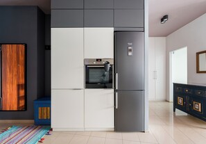 A kitchen with a built-in oven, a refrigerator, and a microwave. - Ochota Superior Apartment (Warszawa)