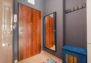 Una puerta de madera, un espejo y un armario azul en una habitación con paredes grises.
