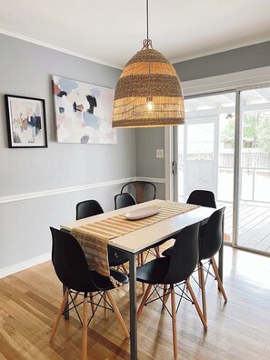A dining area with a table, chairs, a woven pendant light, and artwork on the wall. - Private Cozy Room - 5 min to Hospital and Main in Fredericksburg TX 1 (Fredericksburg)