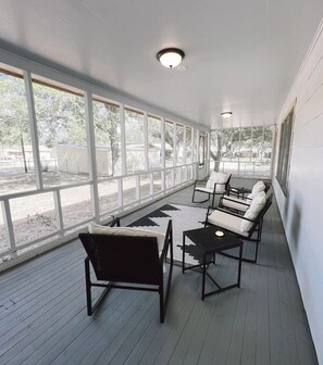 A covered patio with white walls, large windows, and outdoor furniture. - Private Cozy Room - 5 min to Hospital and Main in Fredericksburg TX 1 (Fredericksburg)