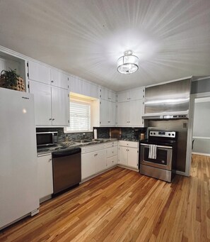 A modern kitchen with white cabinets, a stainless steel oven, a dishwasher, and a microwave. - Private Cozy Room - 5 min to Hospital and Main in Fredericksburg TX 1 (Fredericksburg)