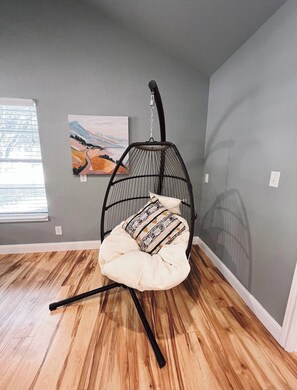 A room with a hanging chair, a painting on the wall, and a window with blinds. - Private Cozy Room - 5 min to Hospital and Main in Fredericksburg TX 1 (Fredericksburg)