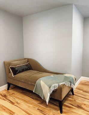 A corner room with a brown sofa, a patterned throw blanket, and a small rug. - Private Cozy Room - 5 min to Hospital and Main in Fredericksburg TX 1 (Fredericksburg)