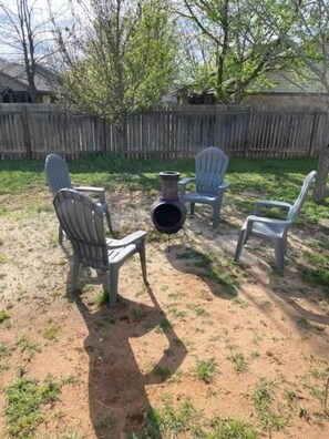 Un espacio al aire libre con tres sillas Adirondack y un brasero.