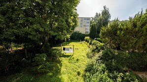Un jardin luxuriant avec un étendoir à linge, un feuillage dense et un bâtiment en arrière-plan.