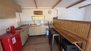 Una cuina compacta amb armaris de fusta, un refrigerador vermell i una barra al costat del taulell.