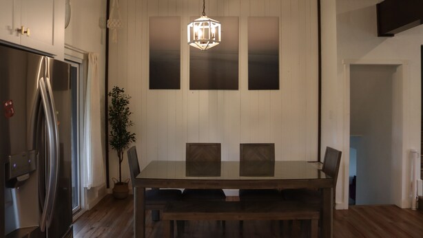 Una cucina moderna con un tavolo da pranzo, sedie, una lampada a sospensione e un frigorifero.