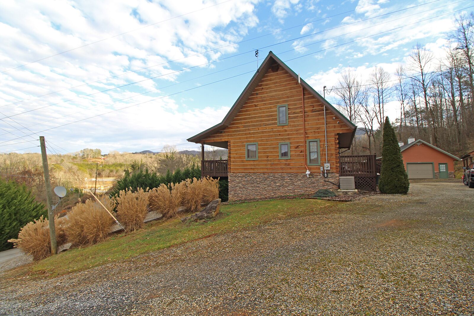 Une cabane en bois avec des fondations en pierre, une cour clôturée et une allée gravillonnée.